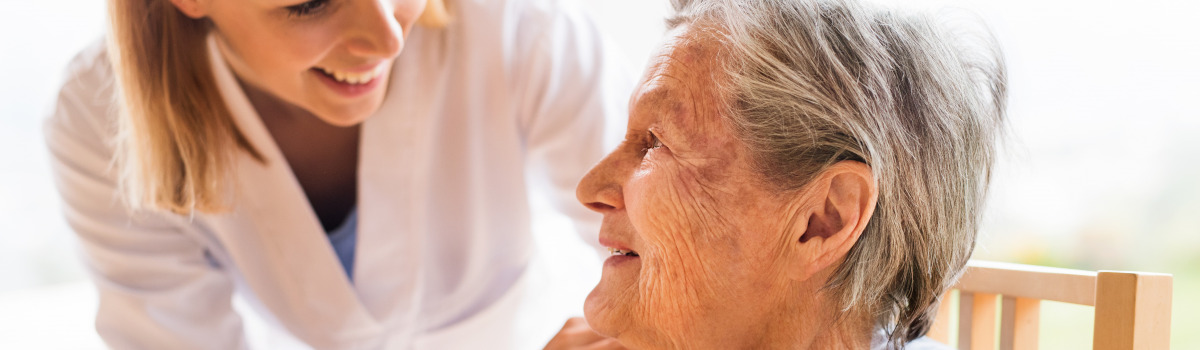 Pflegefachperson kümmert sich um ältere Patientin.