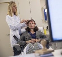 Ärztin befestigt Elektroden am Kopf der Patientin