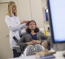Ärztin befestigt Elektroden am Kopf einer Patientin